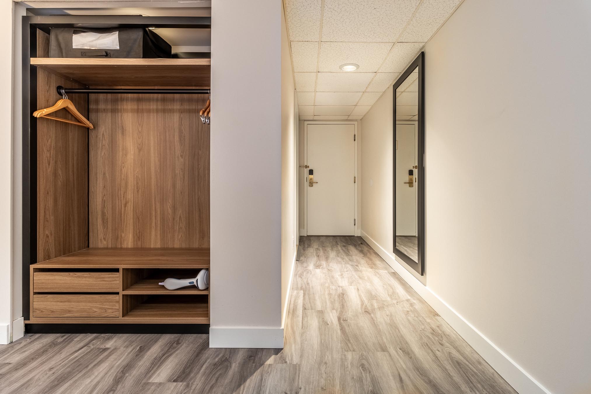 Closet with hanger and safe next to long hallway