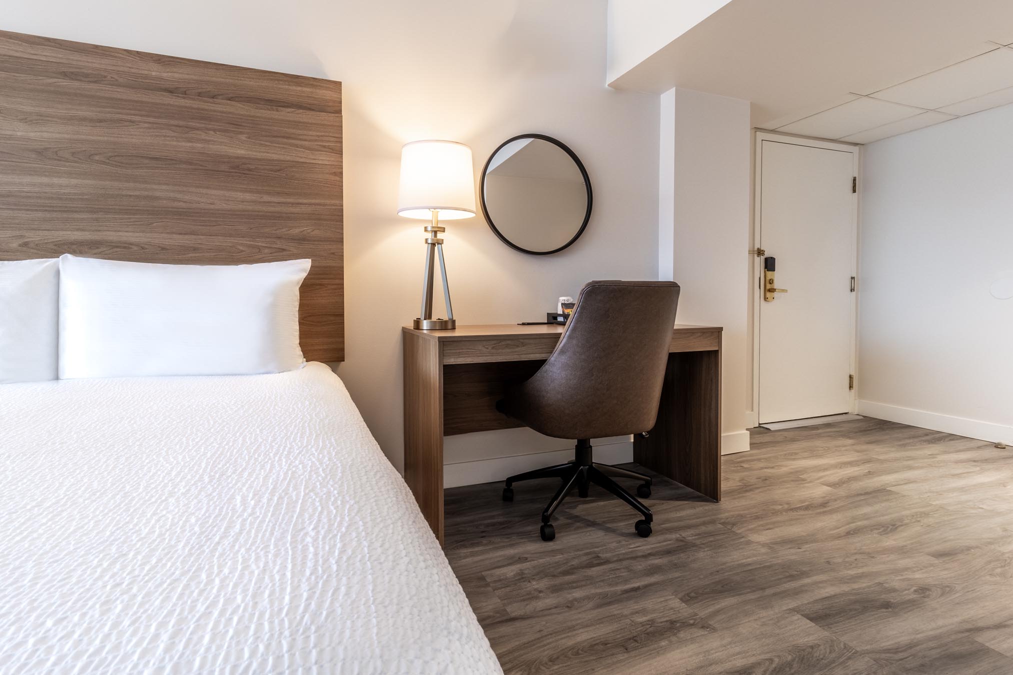 Desk next to queen bed in hotel room